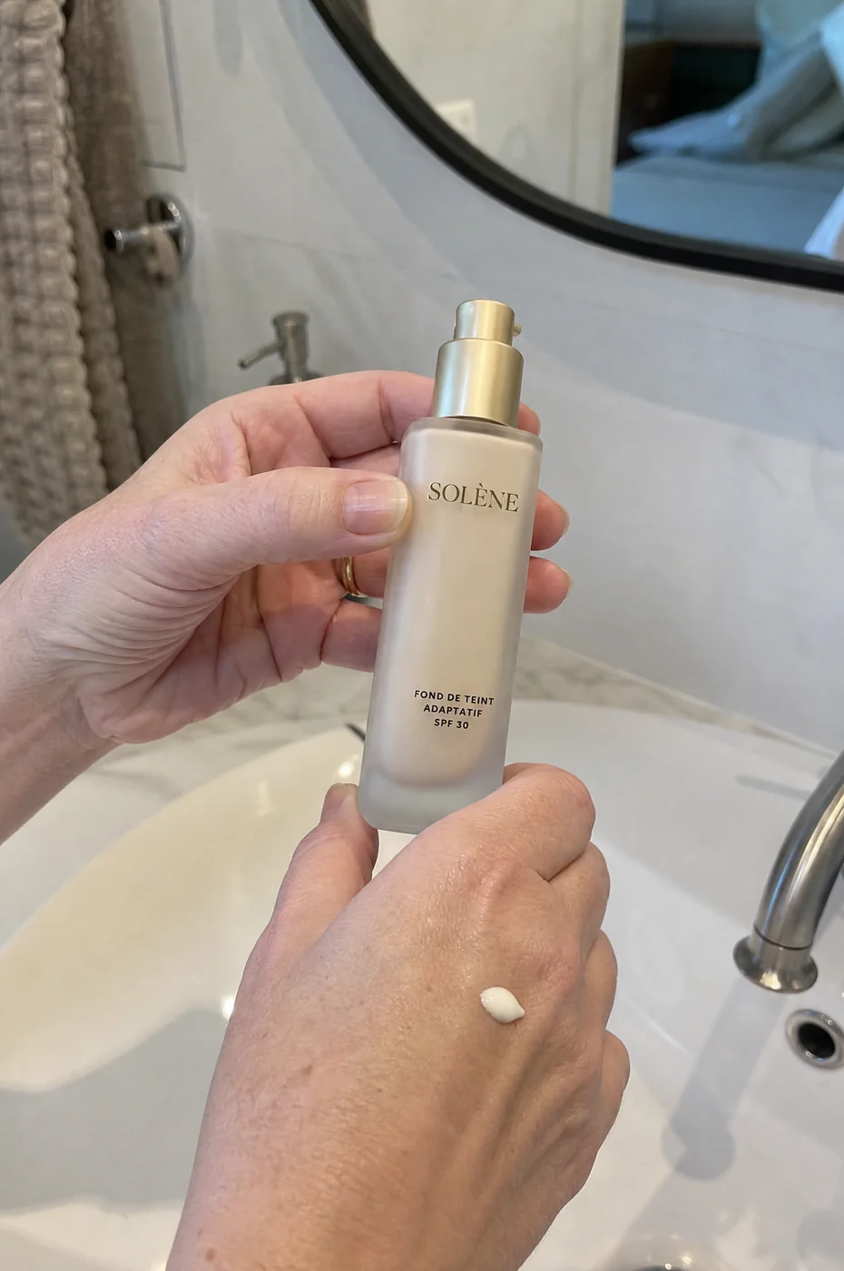 Danielle, 66 ans, tient son flacon de fond de teint Solène au-dessus du lavabo