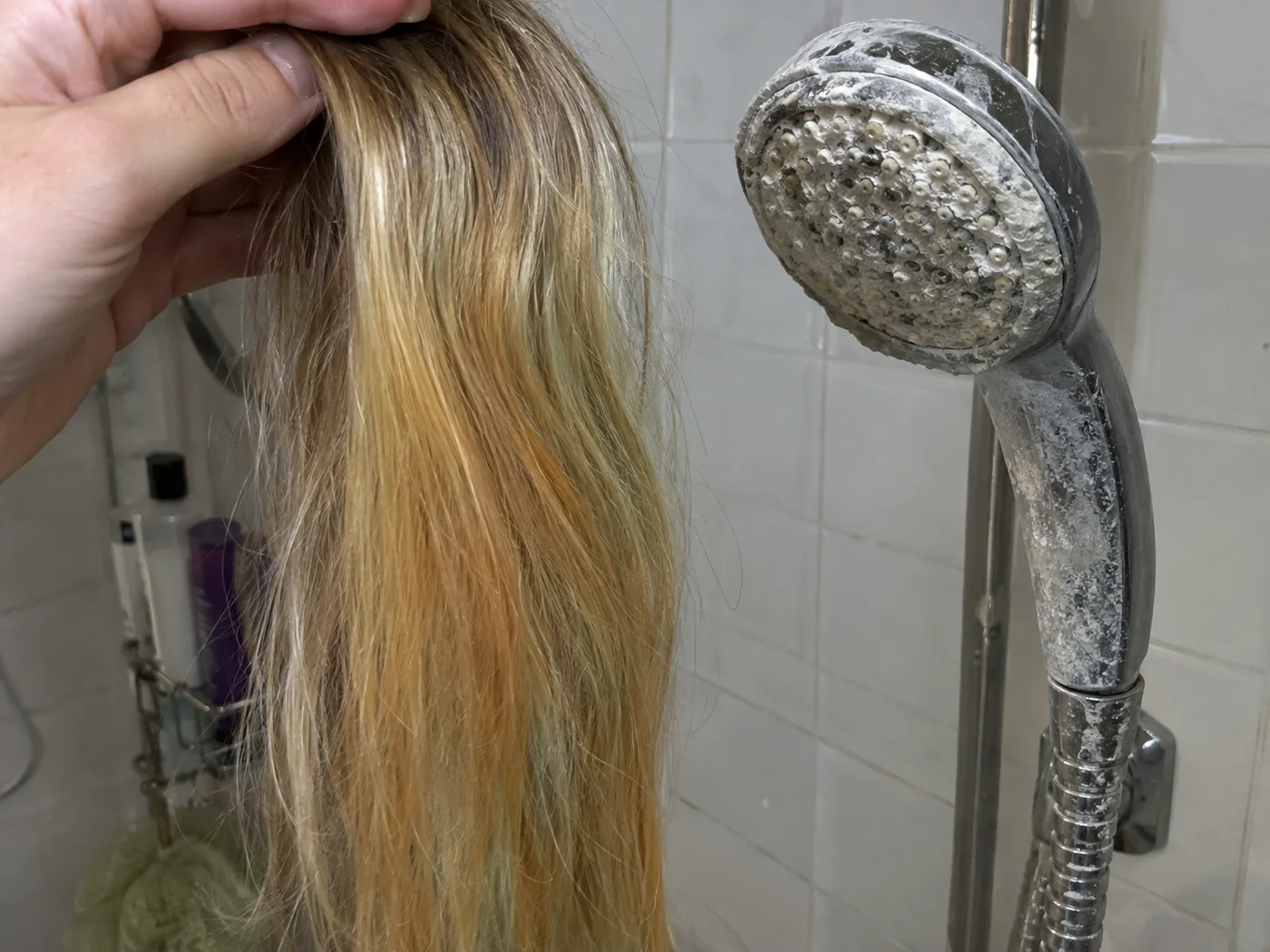 Une mèche de balayage aux reflets jaunis, tenue devant un pommeau entartré